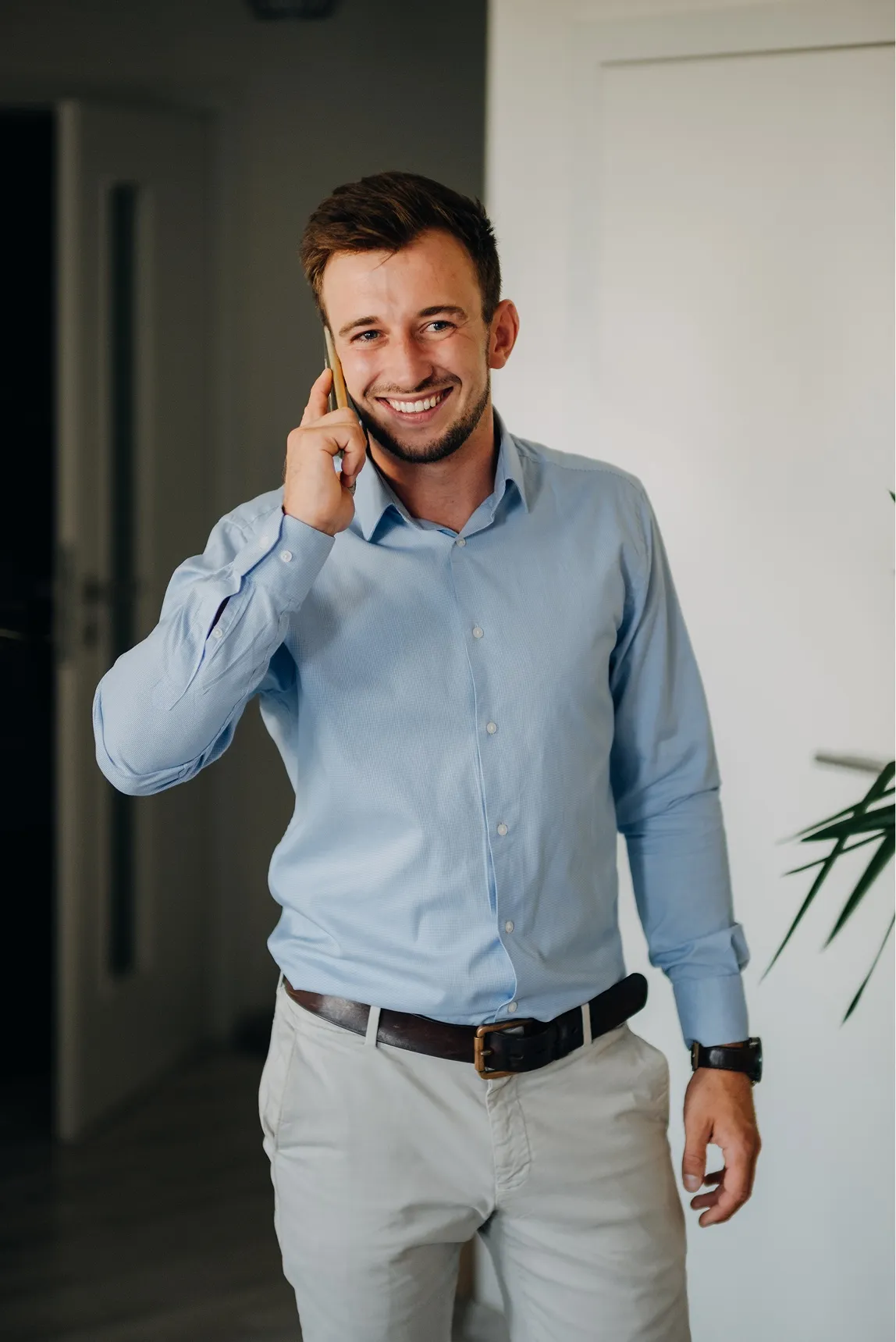 Usměvavý makléř Vojtěch Válka v modré košili telefonuje s klientem